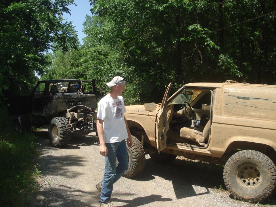 Tan 1989 Ford Bronco II with doors open, parked next to a black off-road vehicle