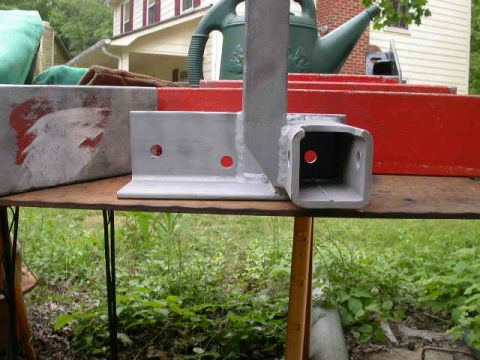 1990 Ford Bronco - A metal trailer hitch receiver part is shown on a table, with red markings visible on a separate object in the background.