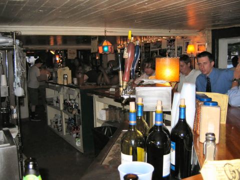 1985 Ford LTD Crown Victoria - A view of a bar interior, showing patrons, beer taps, and bottles of wine on the counter.