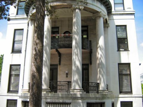 1985 Ford LTD Crown Victoria - A stately white building with classical columns and ornate balconies is seen on a sunny day.