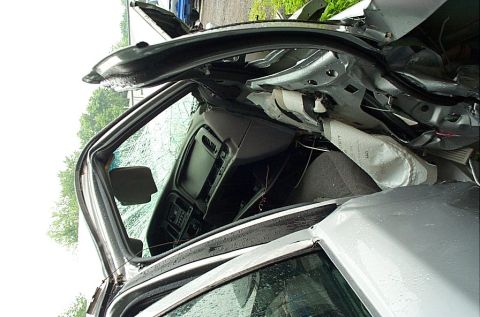 2001 Ford Crown Victoria - Interior view of a severely damaged vehicle, showing deployed airbag and cracked windshield.