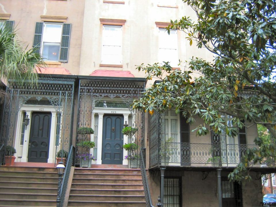 Two adjacent historic row houses with ornate ironwork balconies and dark blue doors. House numbers 421 and 423 are visible
