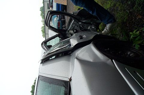 2001 Ford Crown Victoria - A silver sedan sustained significant damage, with its doors ajar, revealing the interior.
