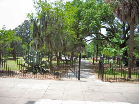 1985 Ford LTD Crown Victoria - A park entrance with a path and trees, likely in a Southern US location due to Spanish moss.