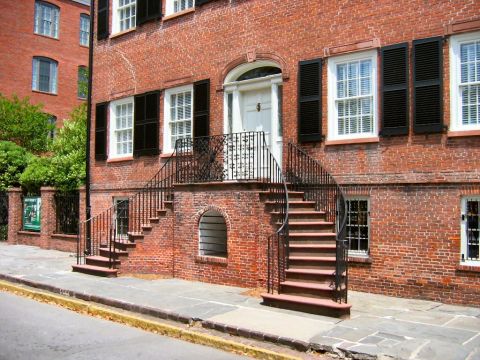 1985 Ford LTD Crown Victoria - A historic brick building features a prominent curved staircase with black railings and shutters on the windows.
