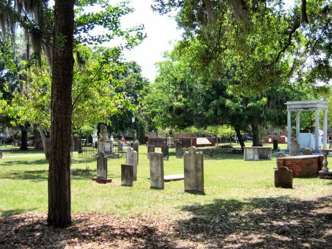 1985 Ford LTD Crown Victoria - A tranquil cemetery scene with weathered gravestones under a canopy of trees.