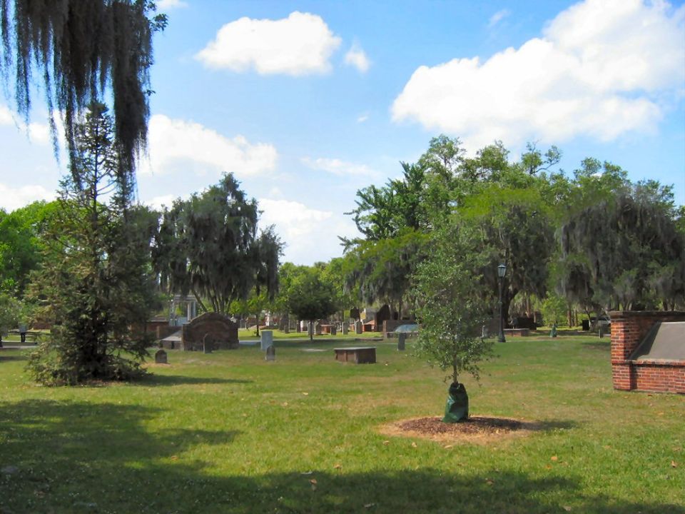 Cemetery scene with gravestones and trees under a cloudy sky