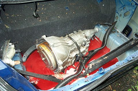 2001 Ford Crown Victoria - A transmission is visible in the trunk of a blue car, surrounded by red fluid.