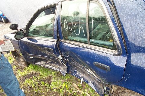 2001 Ford Crown Victoria - This 2001 Ford Crown Victoria sustained heavy damage to its side, with 'ouch!' scrawled on the window.