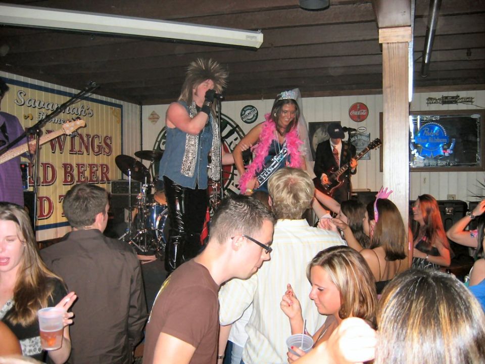 People dancing and watching a band perform on stage at a bar