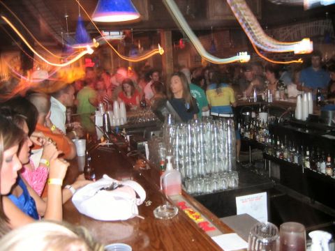 1985 Ford LTD Crown Victoria - A crowded bar scene with patrons and bartenders visible.
