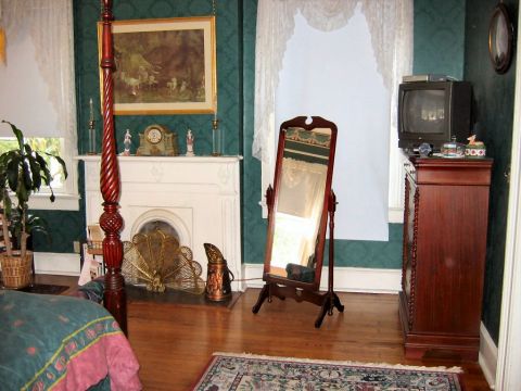 1985 Ford LTD Crown Victoria - A bedroom scene a fireplace, a full-length mirror, a television on a dresser, and a four-poster bed.