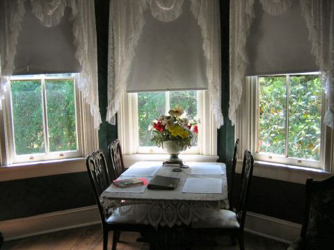 1985 Ford LTD Crown Victoria - Interior scene of a dining room with a table set for a meal, overlooking greenery outside.