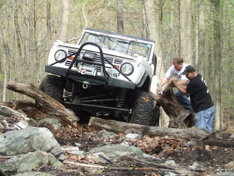 1969 Ford Bronco - This modified SUV navigates a challenging off-road course with assistance from two individuals.
