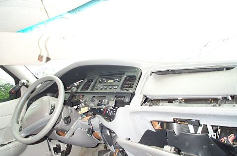 2001 Ford Crown Victoria - Vehicle interior view showing steering wheel, center radio stack and dashboard with trim and wiring removed during repair.