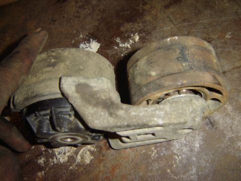 1992 Ford Bronco - A dirty engine mount part is held in a hand, resting on a workbench.