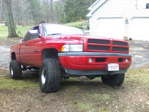 1997 Dodge 1500 - A red 1997 Dodge 1500 pickup truck is shown from a 3/4 front angle, lifted with large tires, parked outdoors.