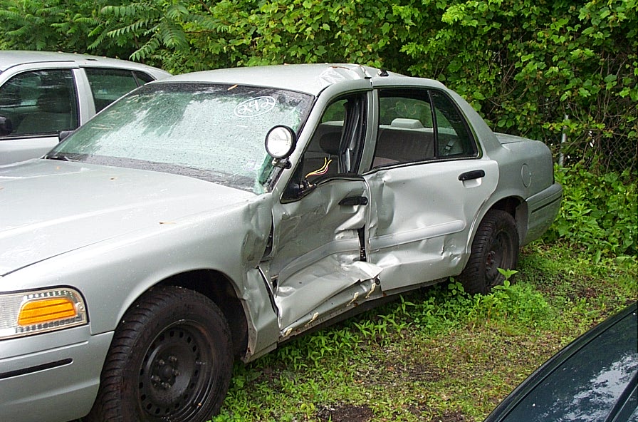 Silver 2001 Ford Crown Victoria with severe driver-side damage, parked outdoors