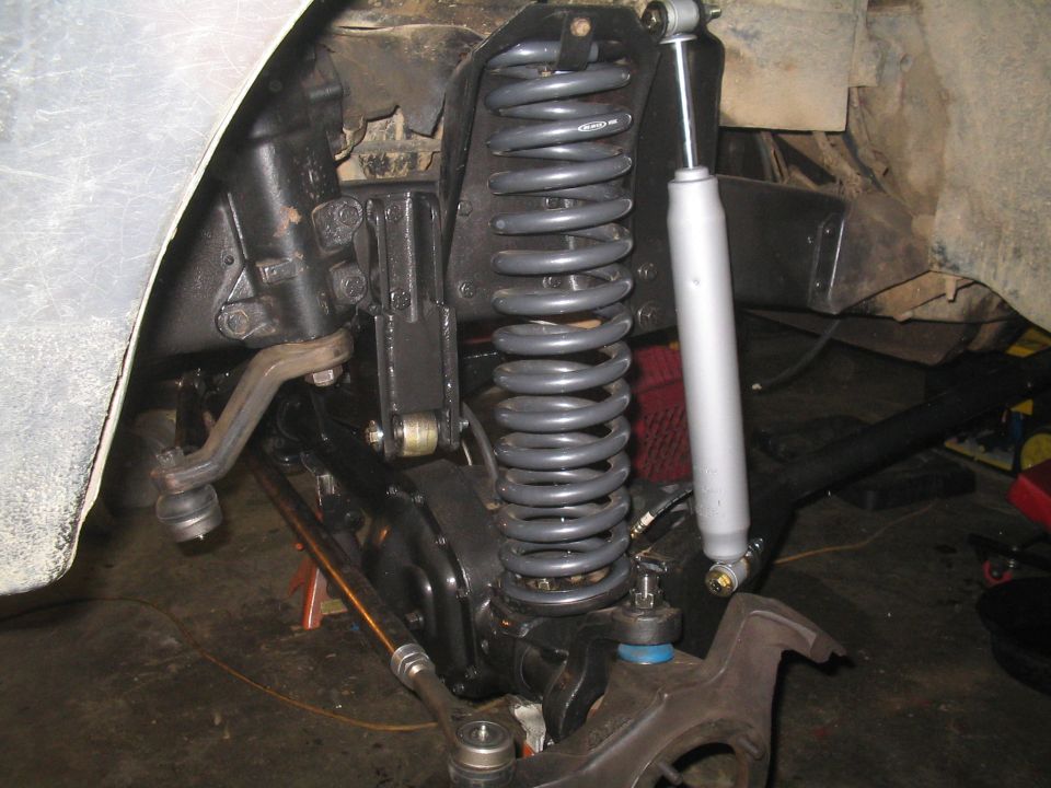 close-up of vehicle's front suspension with large coil spring and shock absorber