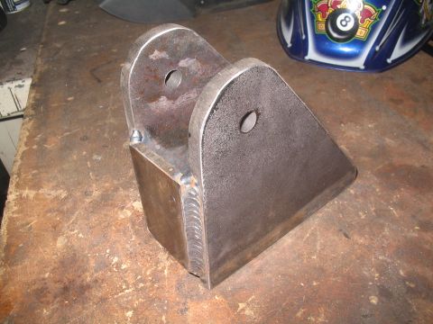 1979 Ford Bronco - A custom-fabricated metal bracket with visible welds sits on a workbench.