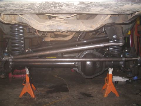1979 Ford Bronco - Close-up of a vehicle's front axle, steering, and suspension components, likely undergoing modification or repair.