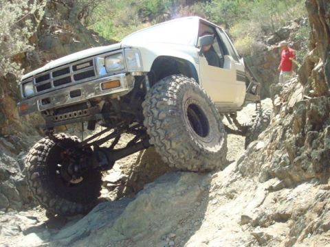 1986 Toyota Hilux - This modified 1986 Toyota pickup truck tackles a challenging off-road course with its impressive suspension and large tires.