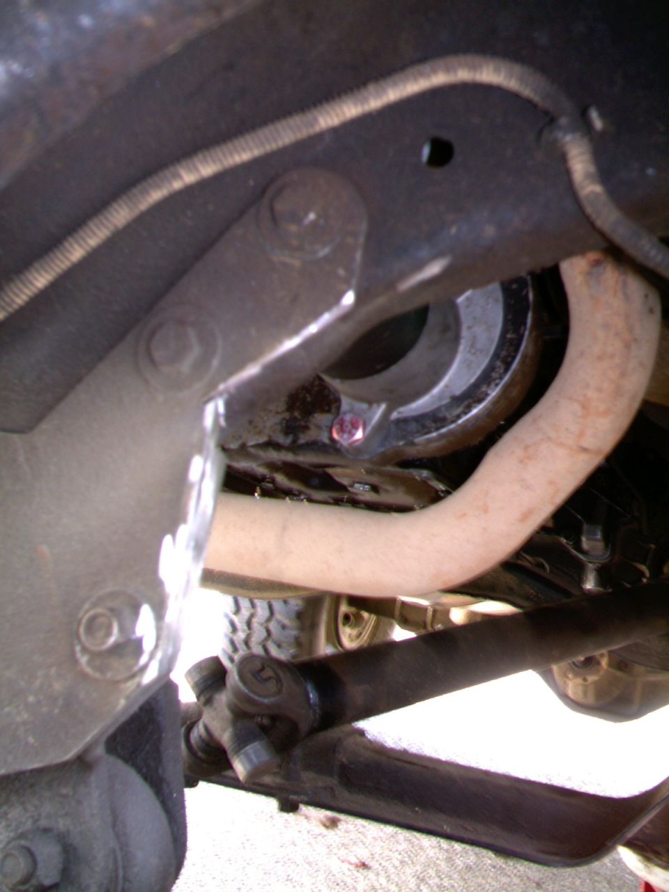 Underside view of a Bronco II showing exhaust pipe, steering linkage, frame bracket and oily front axle area