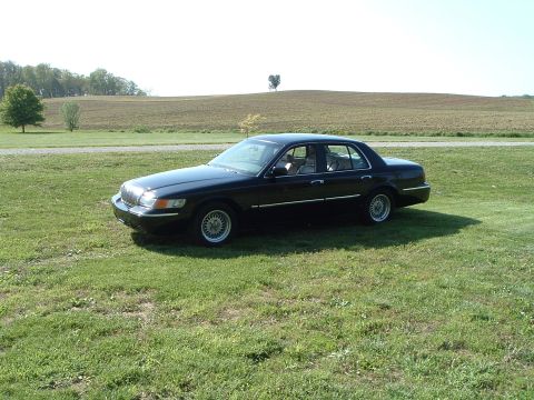 2001 Mercury Grand Marquis - A black 2001 Mercury Grand Marquis sedan is shown from a three-quarter front angle on a sunny day.