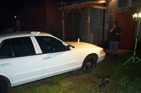 2001 Ford Crown Victoria - A white 2001 Ford Crown Victoria sedan is parked on grass at night, with a person standing in the background.
