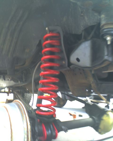 1996 Ford F-150 - The underside of a vehicle shows a bright red coil spring and suspension components.