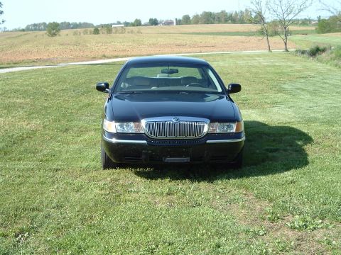 2001 Mercury Grand Marquis - Front view of a black sedan with a prominent chrome grille, parked outdoors on a grassy field.