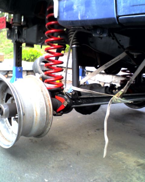 1996 Ford F-150 - Vehicle's rear suspension components, including a red coil spring and shock, are visible with the wheel off.
