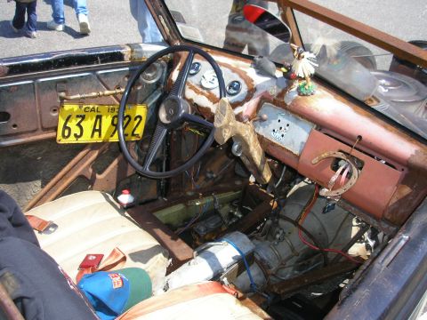 1995 Ford Bronco - The interior of this custom vehicle features a worn dashboard, a unique steering wheel, and a horseshoe hanging from the dash.