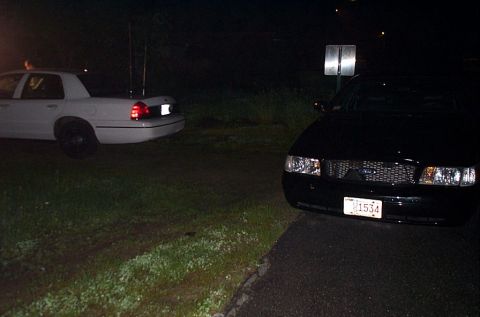 2001 Ford Crown Victoria - Two Ford Crown Victorias are parked side-by-side at night.