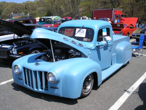 1995 Ford Bronco - A light blue pickup truck is parked at a car show with its hood up.