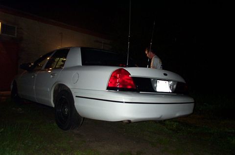 2001 Ford Crown Victoria - A white 2001 Ford Crown Victoria sedan is parked outdoors at night, viewed from the rear.
