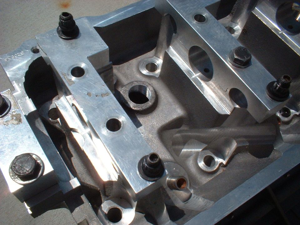Close-up of an aluminum engine block part with bolts and machined surfaces