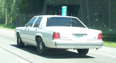 2001 Ford Crown Victoria - Rear view of a white 2001 Ford Crown Victoria driving on a road.
