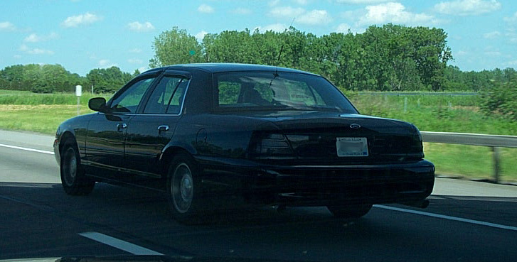 Black 2001 Ford Crown Victoria sedan, rear 3/4 view, driving on highway