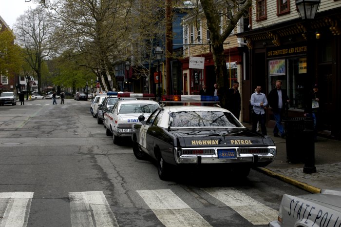 Several police cars parked on a street, one in foreground says HIGHWAY PATROL