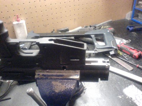 1985 Ford Bronco - A gun receiver is held in a vise on a workbench, surrounded by various tools and a bottle of lubricant.
