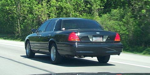 2001 Ford Crown Victoria - Rear view of a black 2001 Ford Crown Victoria driving on a highway.