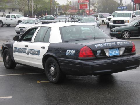 1991 Ford LTD Crown Victoria - black-and-white Ford Crown Victoria cruiser lettered Seekonk Police with 911 markings, shown from the rear three-quarter on a wet lot.