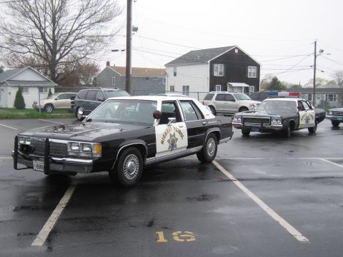 1991 Ford LTD Crown Victoria - Two black-and-white California Highway Patrol Ford LTD Crown Victoria sedans with push bars parked in a wet residential lot.