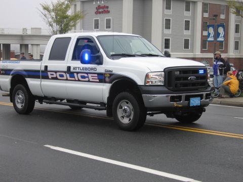1991 Ford LTD Crown Victoria - White Attleboro Police Ford Super Duty crew cab pickup with blue strobe lights drives past spectators.