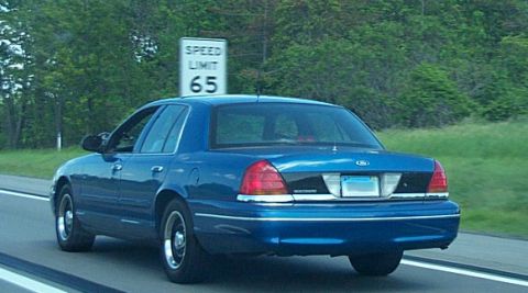 2001 Ford Crown Victoria - A blue 2001 Ford Crown Victoria is seen from the rear on a highway with a speed limit sign.