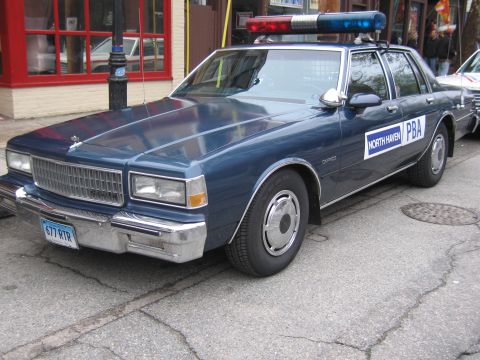 1991 Ford LTD Crown Victoria - Front three-quarter view of a dark blue Chevrolet Caprice North Haven PBA police sedan parked curbside, plate 677 RTR.