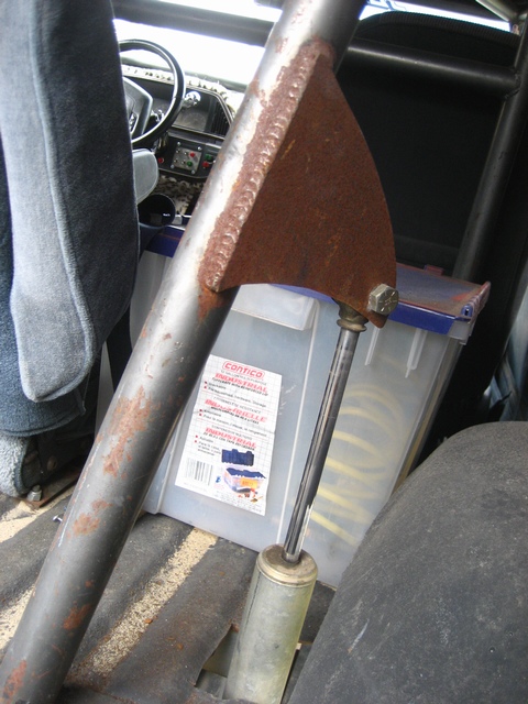 1989 Ford Bronco - Interior view of a vehicle showing a roll cage, dashboard, and a storage container with yellow coiled items inside.