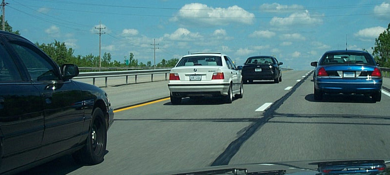 Cars on a highway under a partly cloudy sky