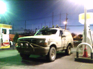 1995 Ford Bronco - A tan Ford Bronco is parked at a gas station at dusk.